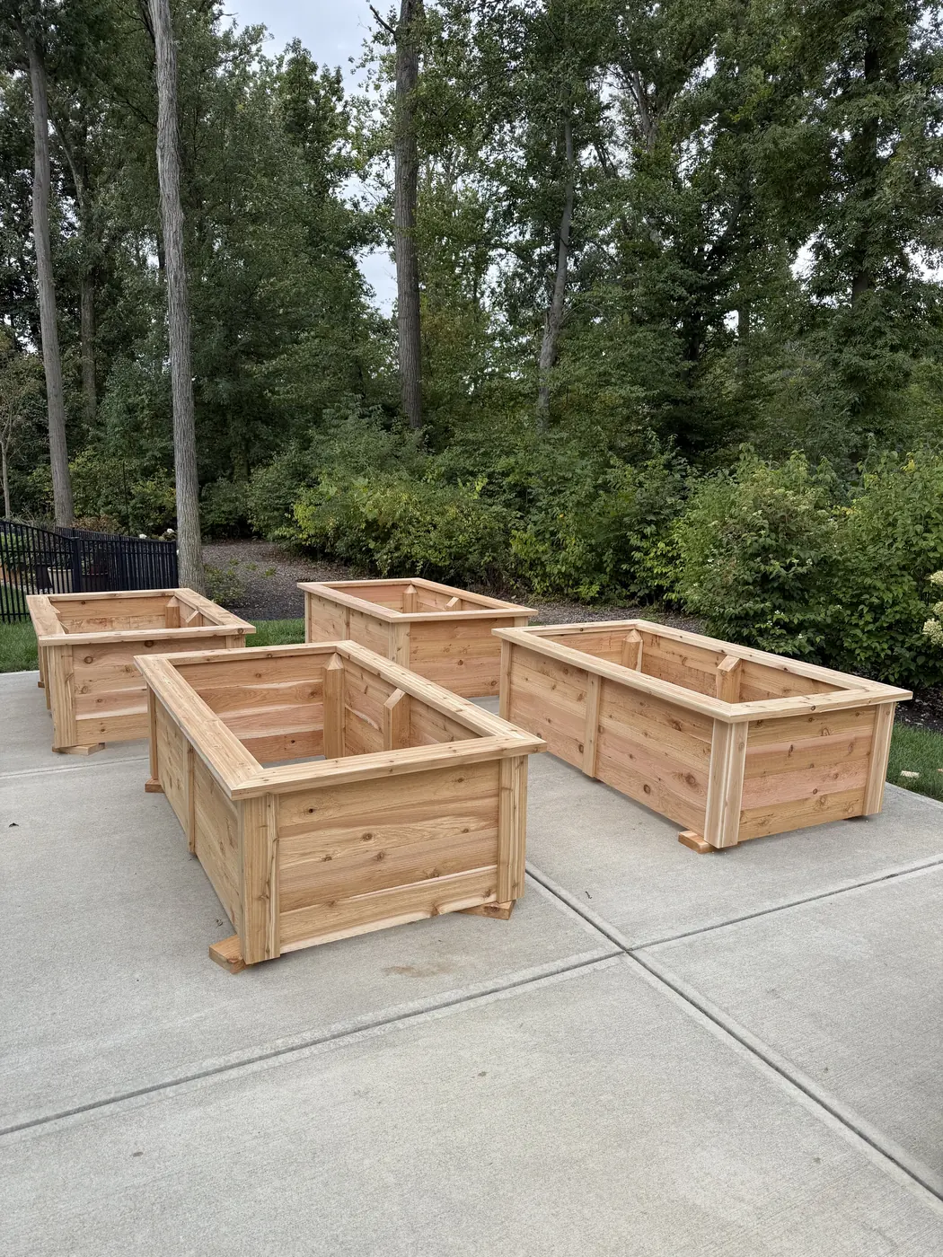 Four finished cedar raised garden beds on a driveway