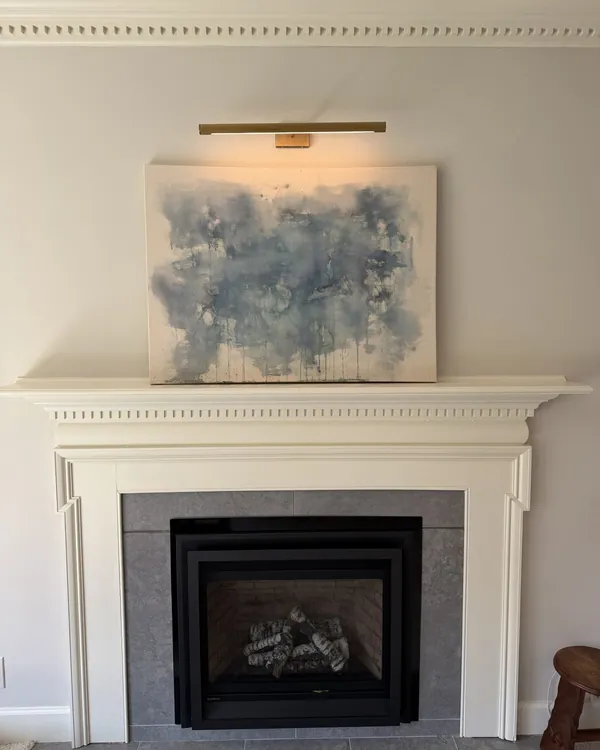 Brass picture light installed above fireplace mantel art