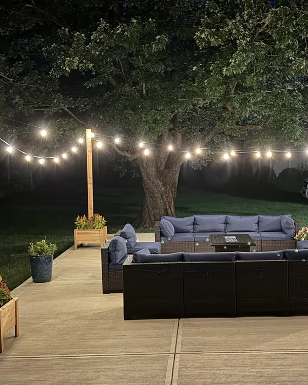 Cedar posts carrying string lights over a backyard patio