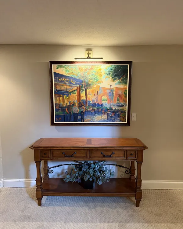 Picture light installed above framed art over a console table